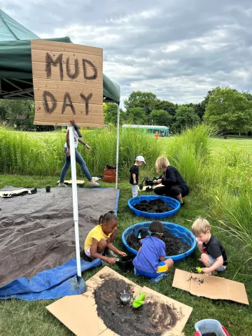 mud day sign and children playing with mud