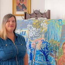 Photo of artist Ashley Menth standing with a colorful impressionist painting