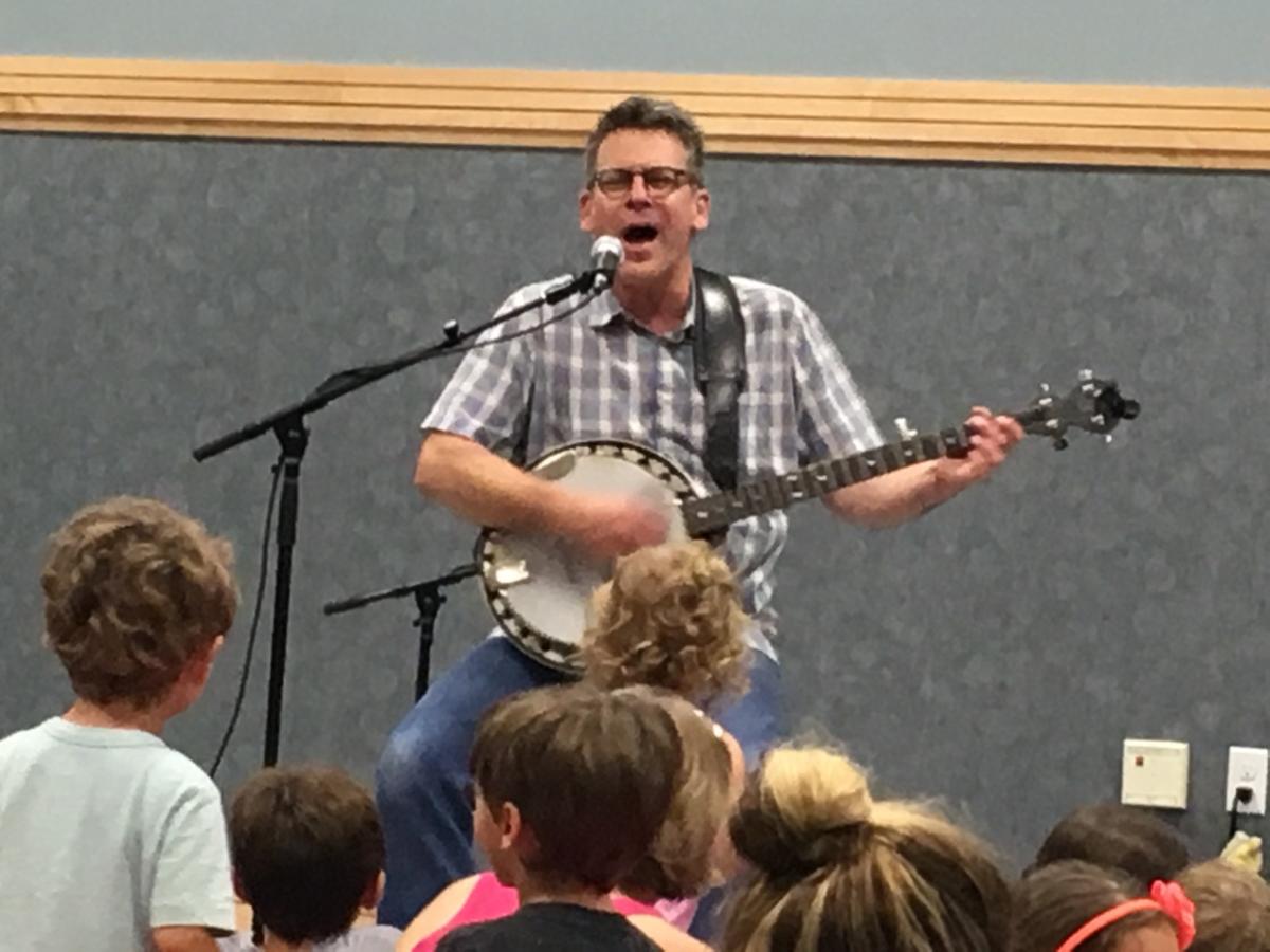 man playing banjo in front of kids