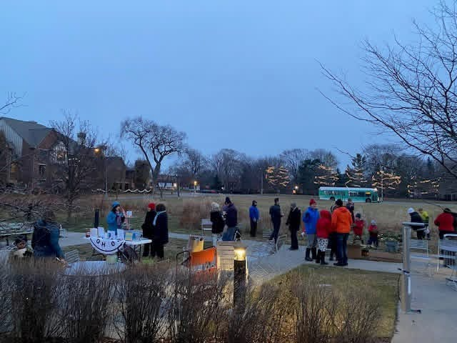 Group of people gathered outside the library with lights and tables set up